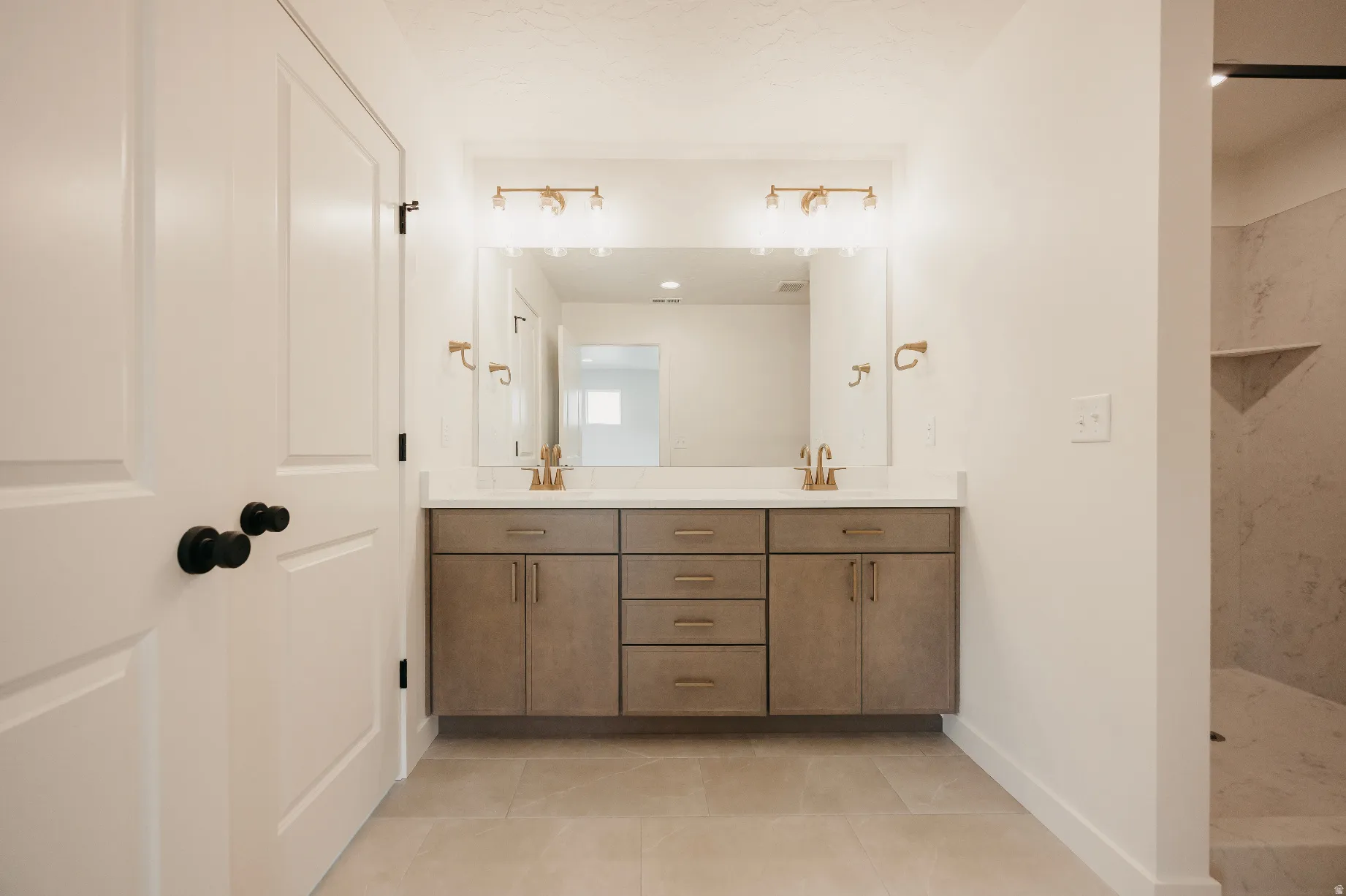 Dual vanity with integrated sinks, brushed gold fixtures, a large mirror, and recessed lighting
