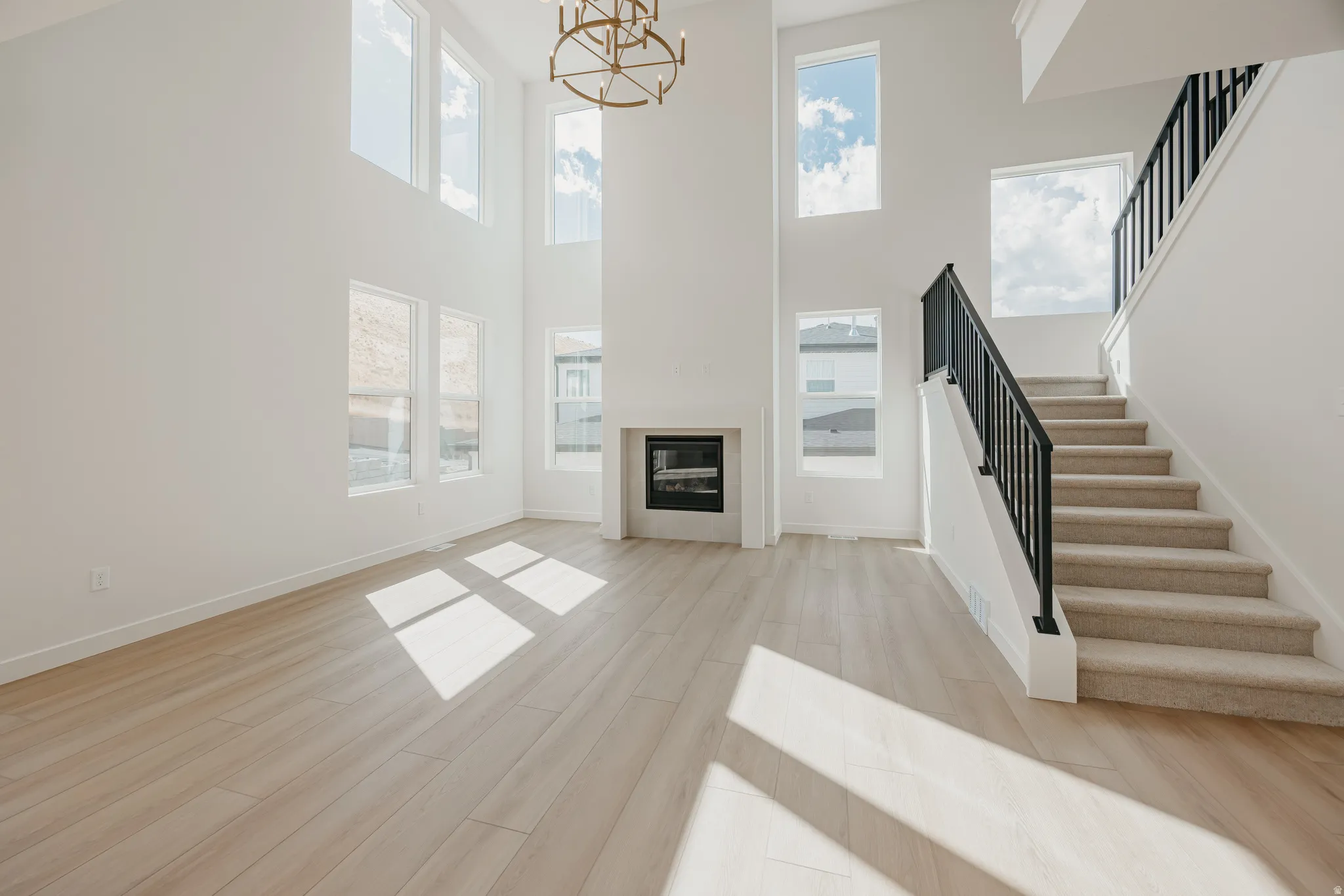 Two-story living area with high ceilings, large windows, a fireplace, and wood-finish flooring