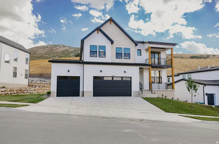 Modern farmhouse exterior with board and batten siding, brick accents, and a two-story balcony