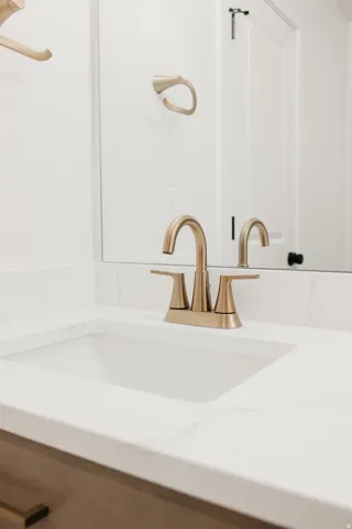 White countertop with integrated sink, brushed gold-finish faucet, and coordinating towel ring
