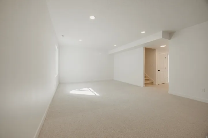 Recessed lighting, light-colored carpeting, white interior walls, interior staircase, white interior door with black hardware