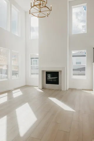 Two-story living area with high ceilings, multiple windows, a modern fireplace, and light wood-finish flooring