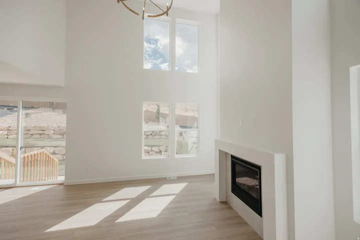 Soaring ceilings, abundant natural light, recessed fireplace, wood-finish flooring, and a contemporary light fixture