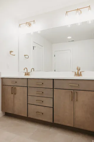 Dual vanity featuring a white countertop, wood-finish cabinetry, and gold-tone fixtures