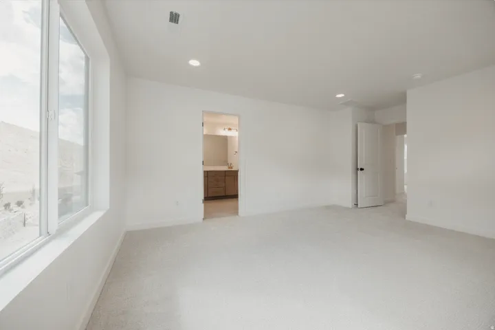Recessed ceiling lighting, light-toned carpet, white walls, and a large window