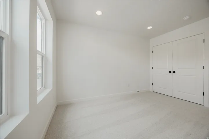 Double windows with white trim, recessed lighting, and light-toned carpeting