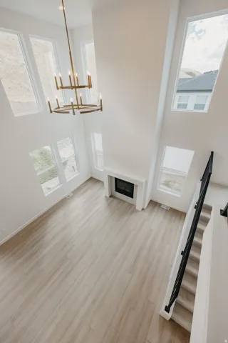 Soaring ceilings with a multi-tiered chandelier, a built-in fireplace, wood-finish flooring, and expansive windows