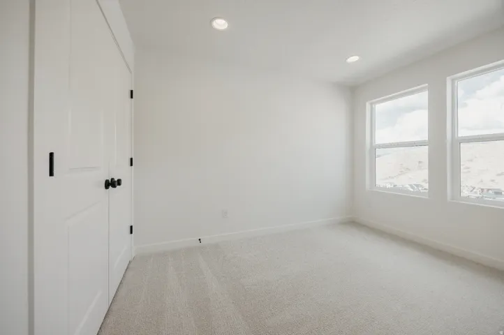 White walls, two windows, recessed lighting, white trim, and light gray carpeting
