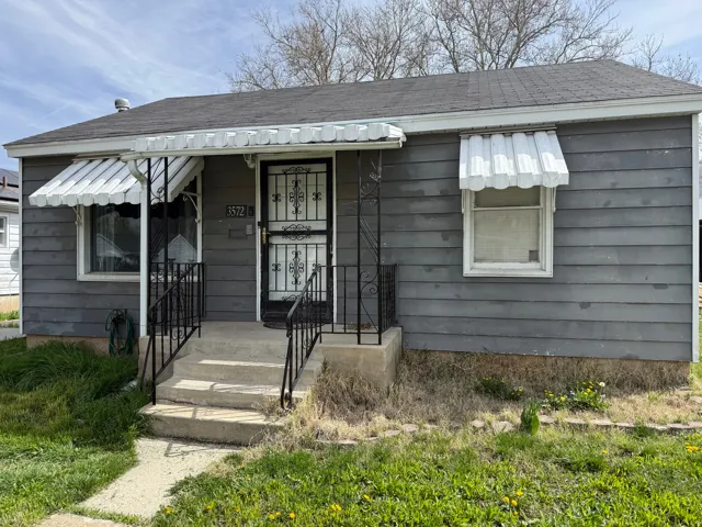 Siding exterior with multiple window awnings, concrete steps, and wrought iron railings