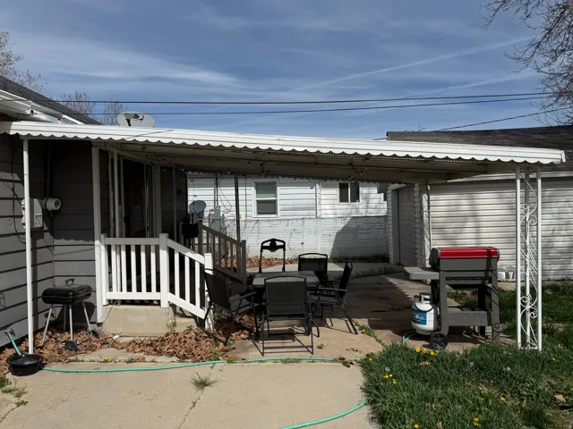Concrete patio with an overhead awning, white railing, and exterior siding