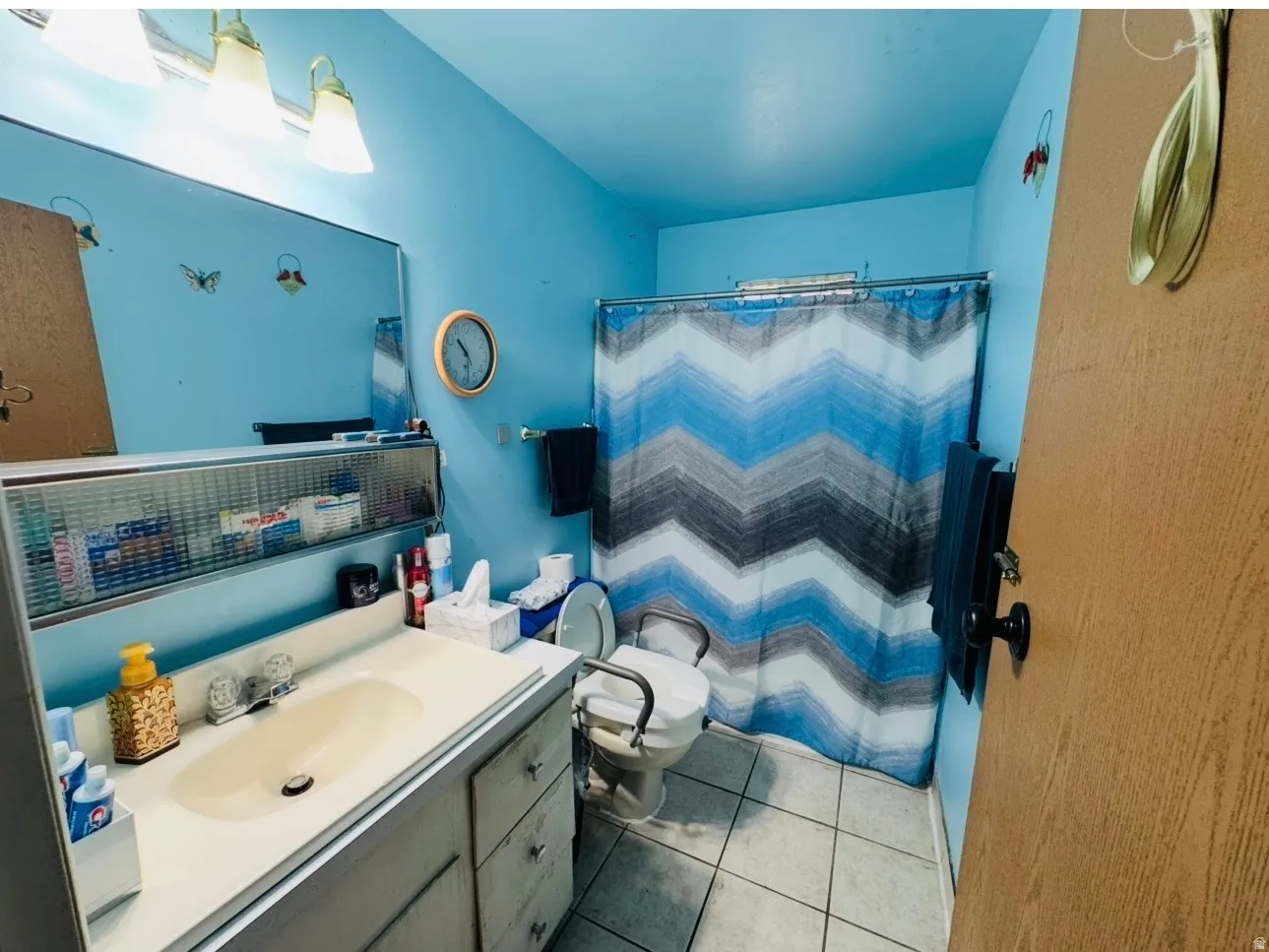 Bathroom featuring a vanity with an integrated sink, wall-mounted mirror, and tile flooring