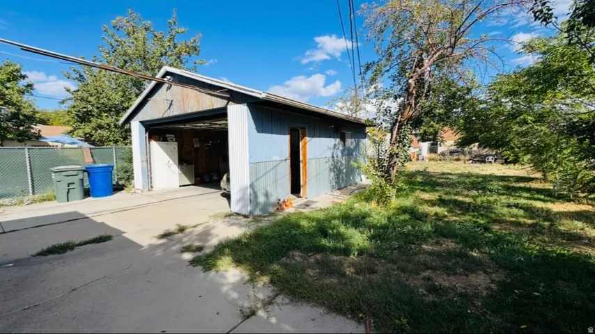 Detached garage with corrugated metal siding, an open garage door, and a paved driveway
