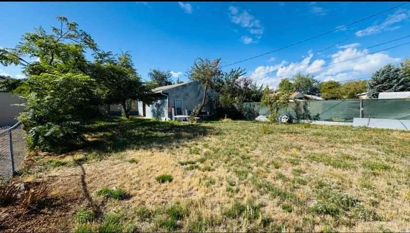 Expansive lot with chain-link fencing, mature trees, and a partial building structure