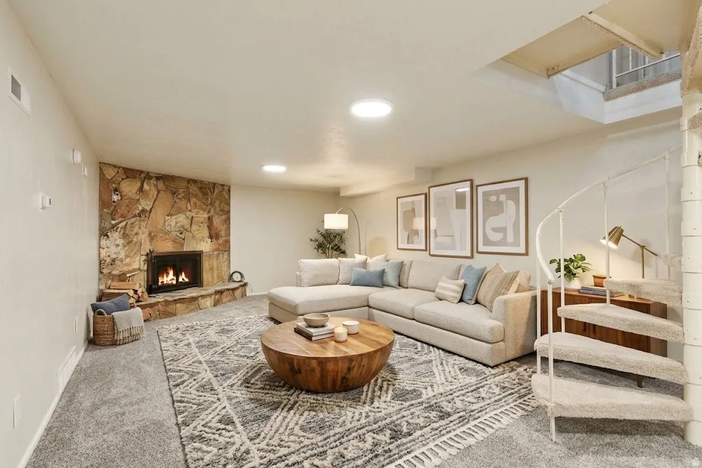 Stone fireplace with a hearth, recessed lighting, and carpeted flooring