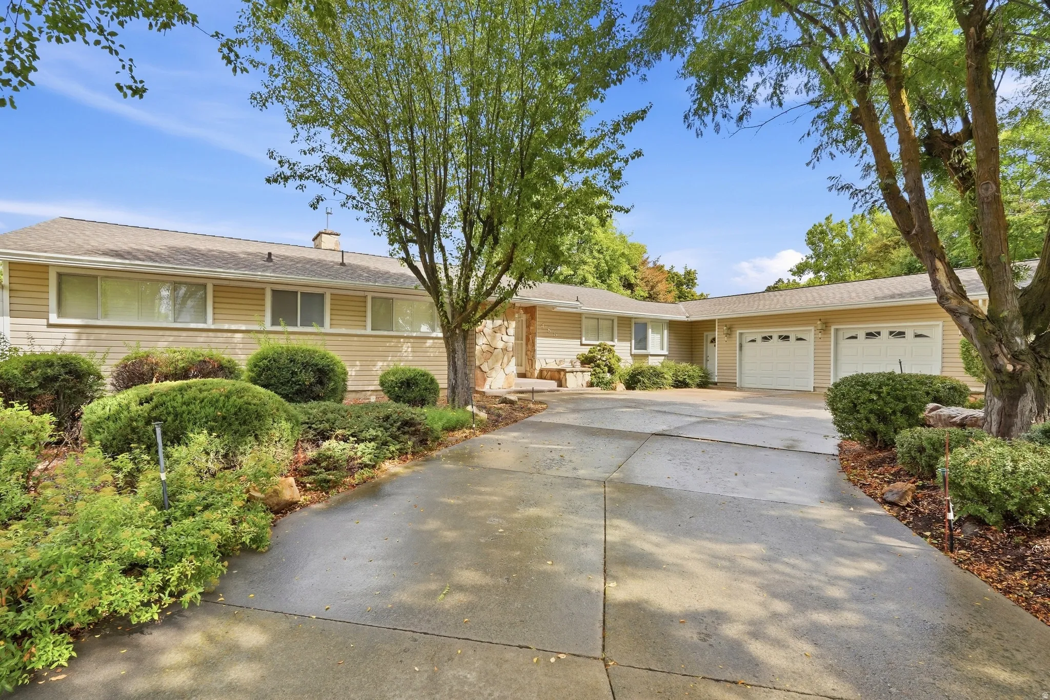 Ranch-style exterior with horizontal siding, stone accents, and a dual garage