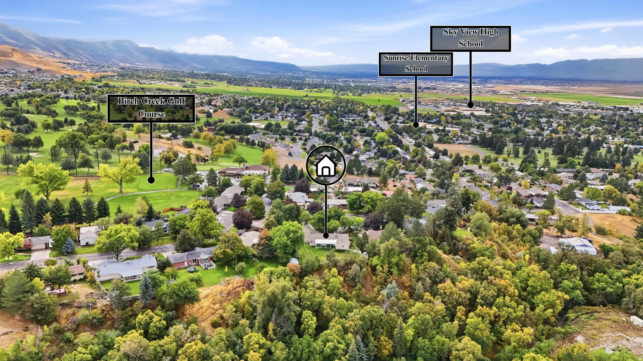 Aerial perspective of a verdant landscape featuring a residential area, a golf course, and distant mountains