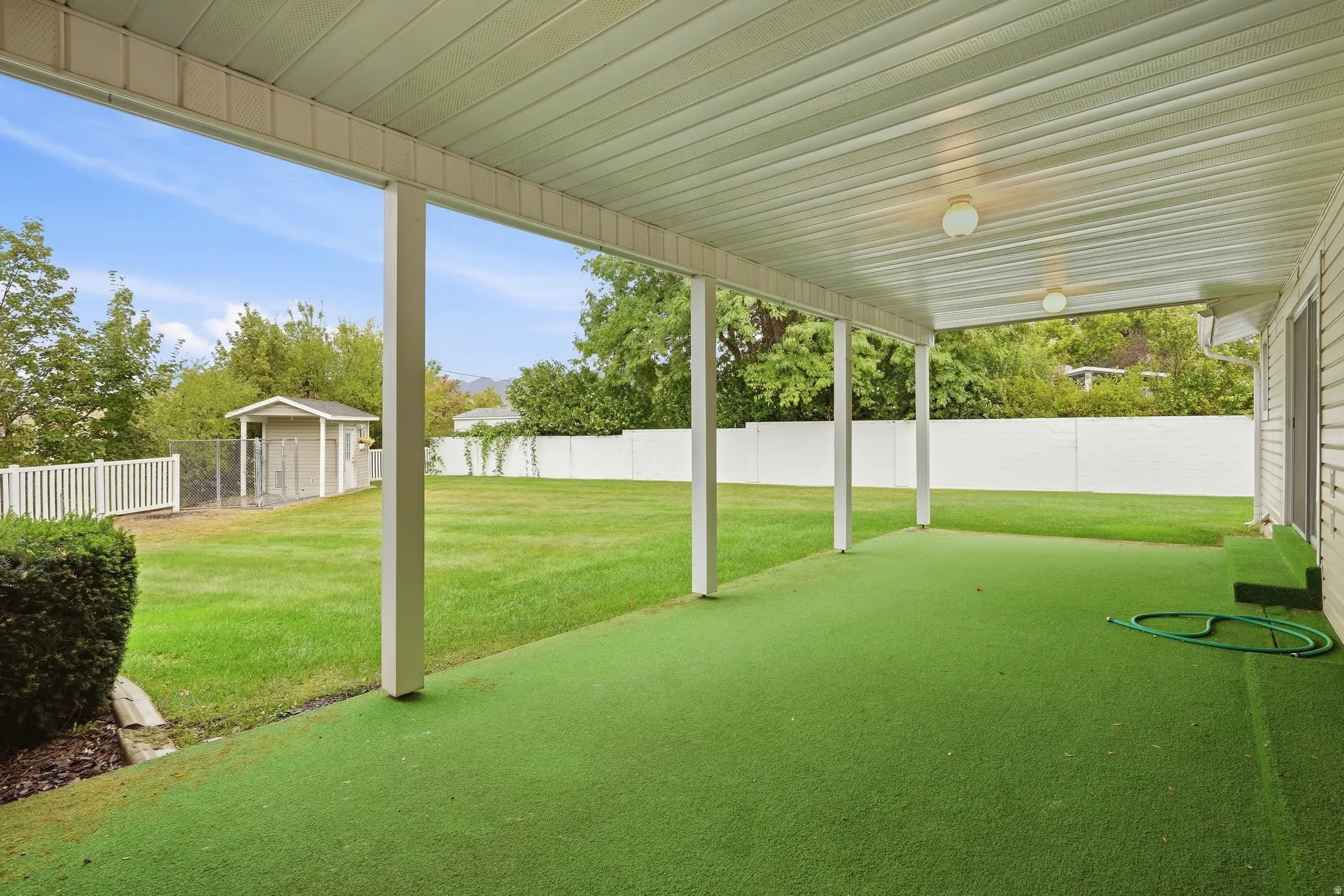 Covered patio with artificial turf surfacing, supported by white posts