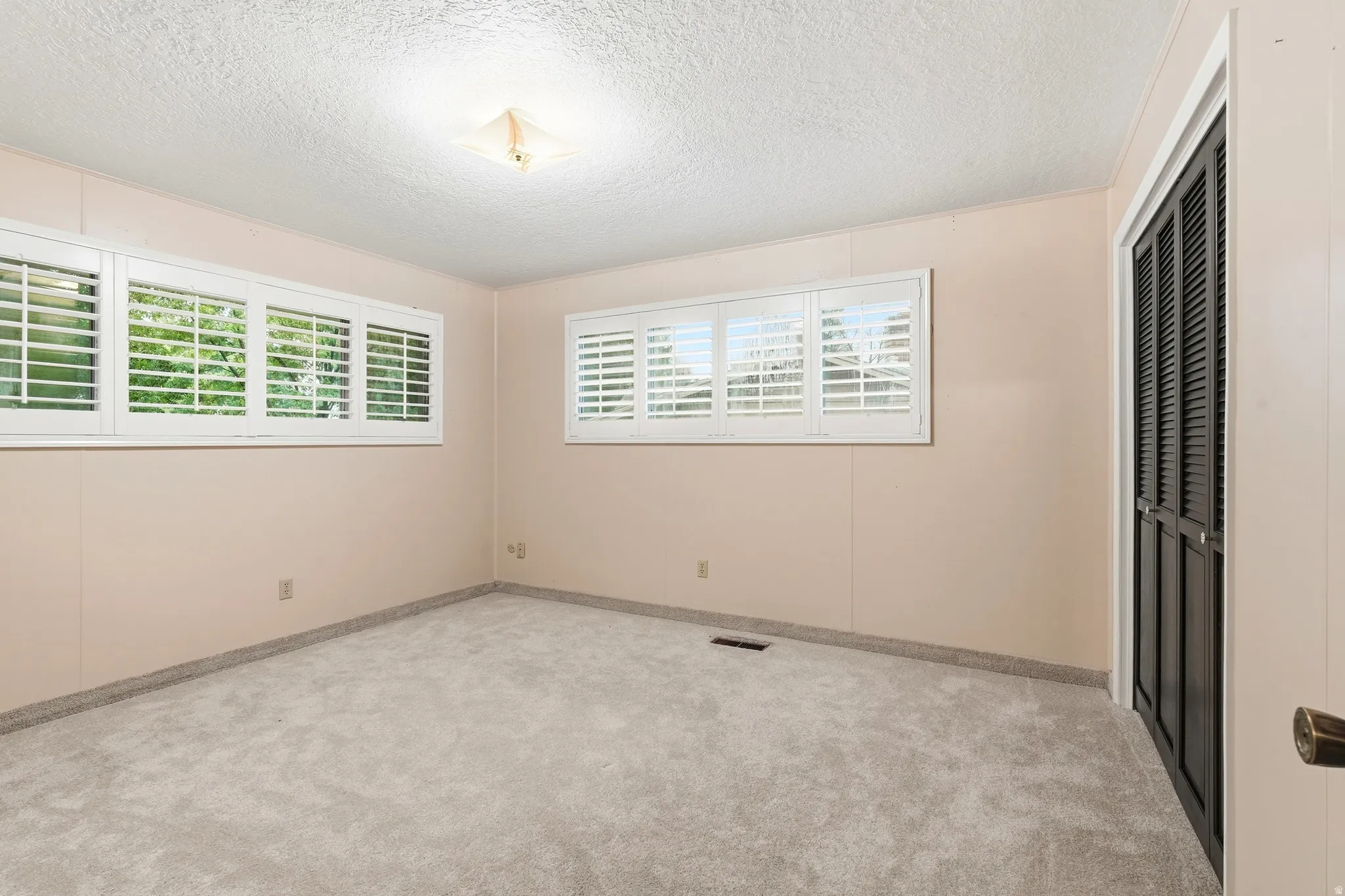 Light-colored carpeting with textured ceiling