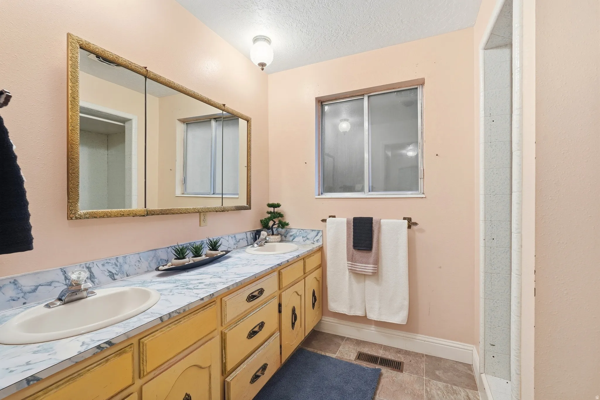 Dual vanity with integrated sinks, framed medicine cabinet, and a window with privacy glass