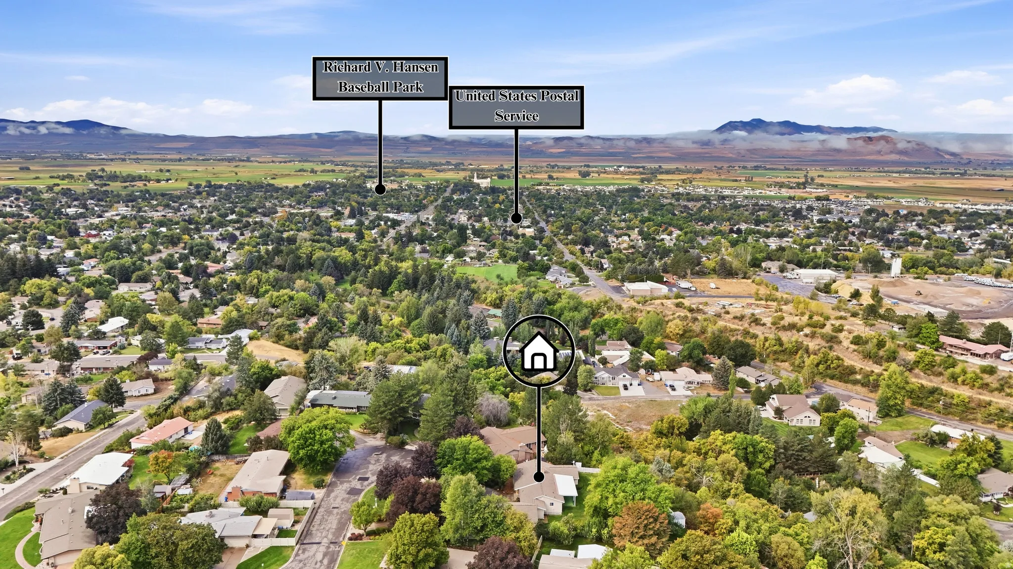 Aerial perspective showcasing a residential neighborhood with abundant mature trees and distant mountain ranges