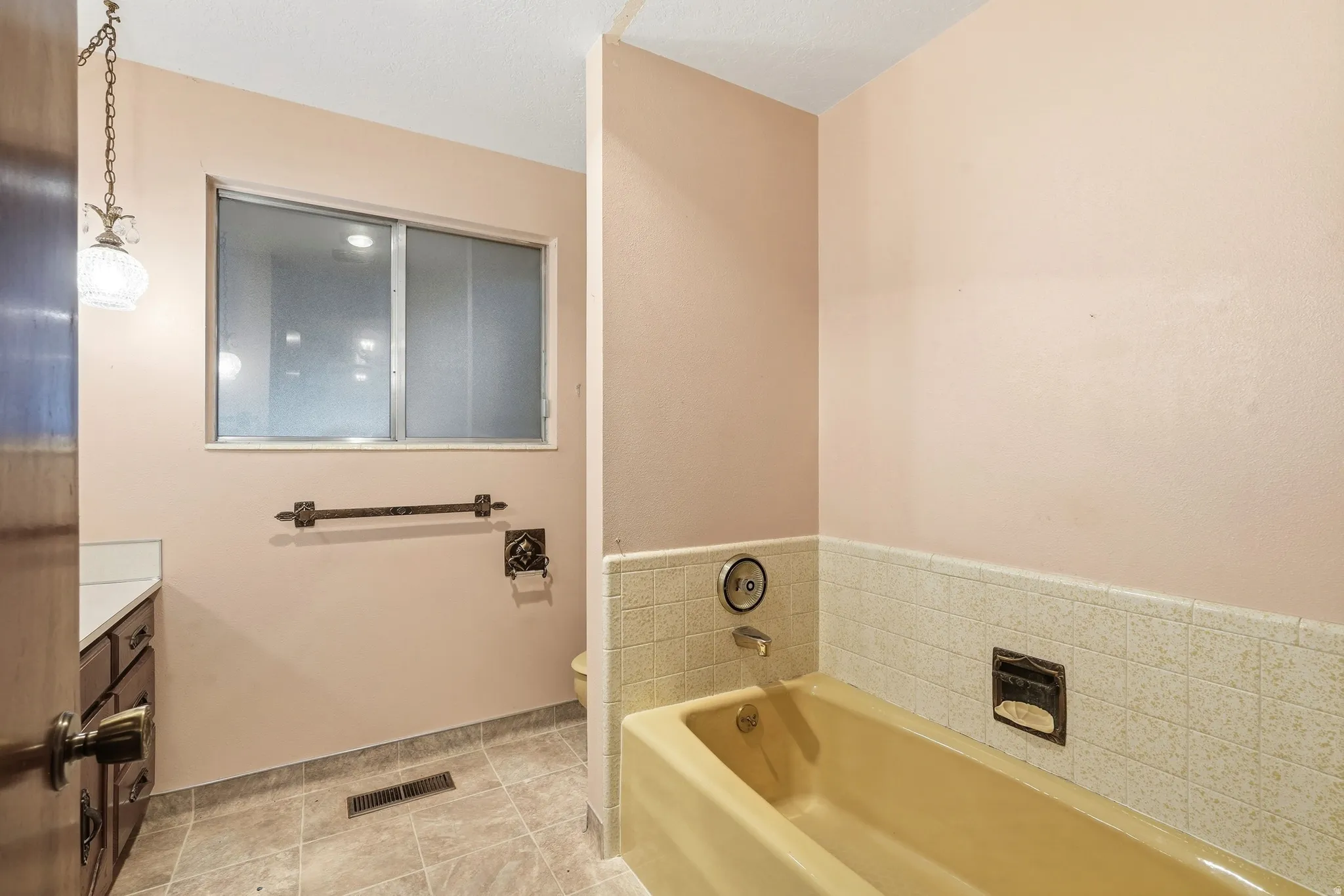 Tiled flooring and a built-in bathtub with tiled surround