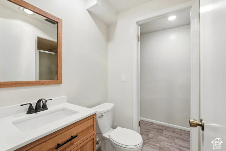 Bathroom featuring a wood-finish vanity with an integrated white sink, bronze-finish faucet, and coordinating wood-frame mirror