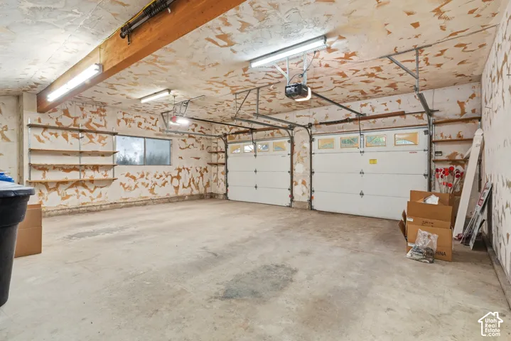 Concrete flooring, two automatic garage door openers, two overhead fluorescent light fixtures, two garage doors with window panels, and built-in shelving