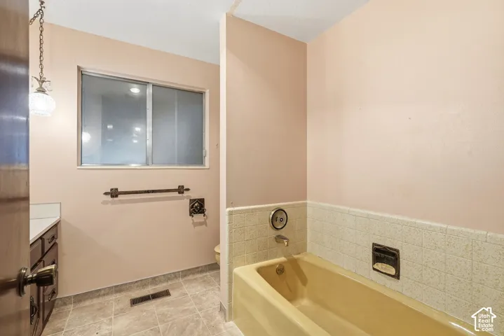 Tiled flooring and a built-in bathtub with tiled surround