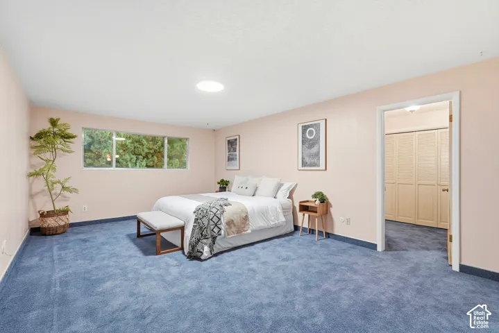 Light pink walls, blue carpeting, and a window with exterior tree scenery