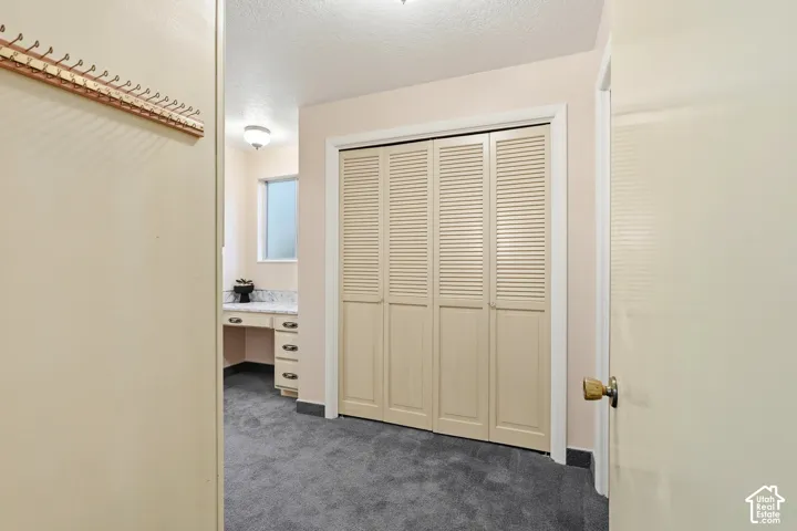 Built-in vanity with a light-colored countertop, louvered bi-fold closet doors, and recessed window