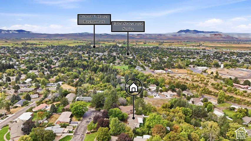 Aerial perspective showcasing a residential neighborhood with abundant mature trees and distant mountain ranges