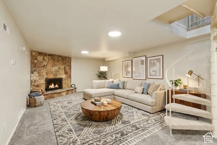 Stone fireplace with a hearth, recessed lighting, and carpeted flooring