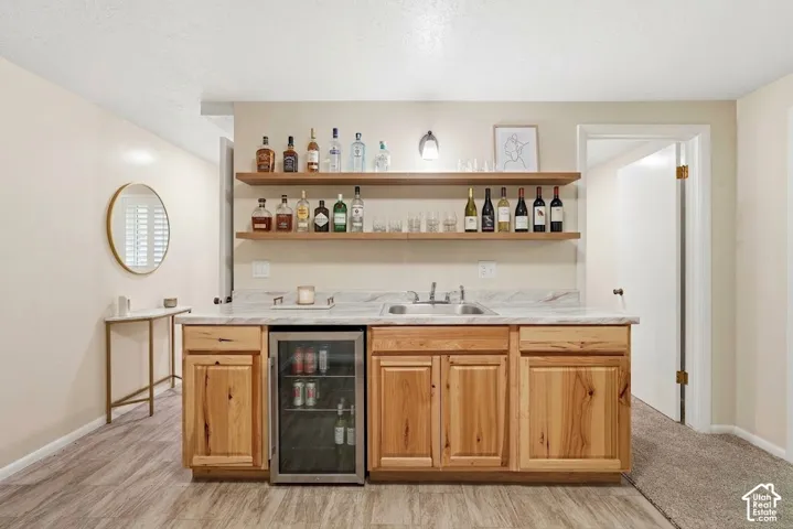 Wet bar with wood cabinetry, light-toned countertop, and integrated beverage refrigerator
