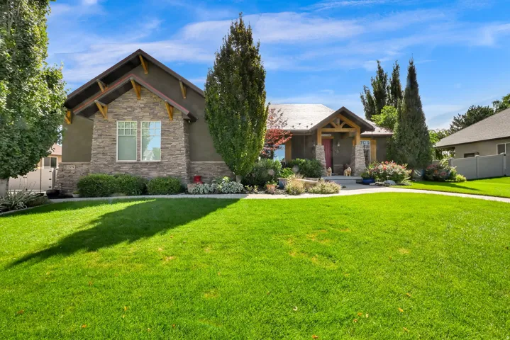 Stone facade with natural wood accents, covered entry, and a vibrant green lawn