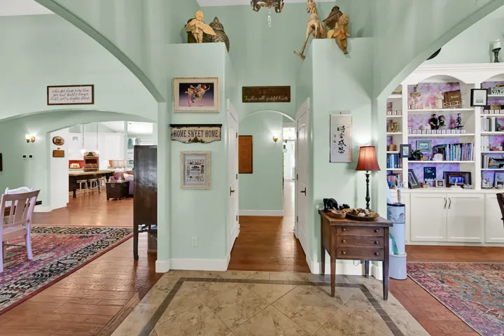 Arched doorways, built-in shelving, wood-finish flooring, and a tiled entryway