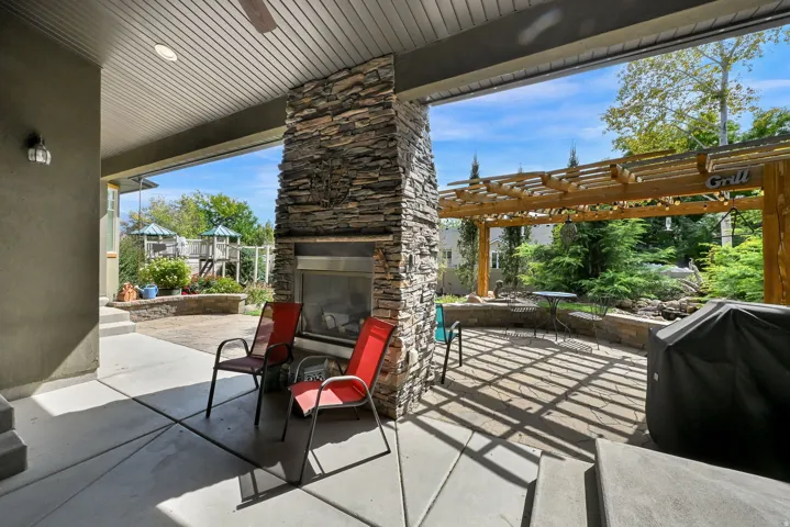 Covered patio featuring a stone-clad fireplace and ceiling fan