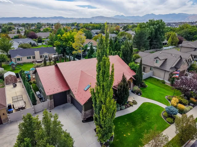 Striking Contemporary Home Featuring a Distinctive Pitched Metal Roof in Warm Rose Tones, Anchored by Tall Columnar Evergreens and Complemented by Manicured Landscaping