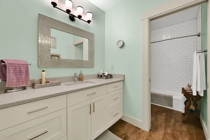 Bathroom vanity featuring a single basin sink, white cabinetry with silver hardware, a light-colored countertop, and a framed mirror