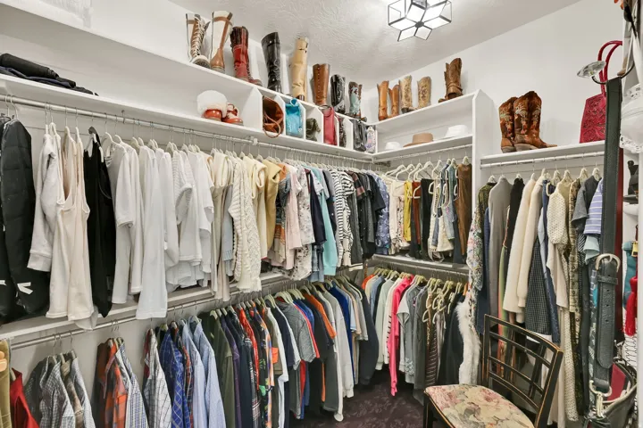 Built-in custom shelving, multiple clothing rods, and overhead lighting fixture