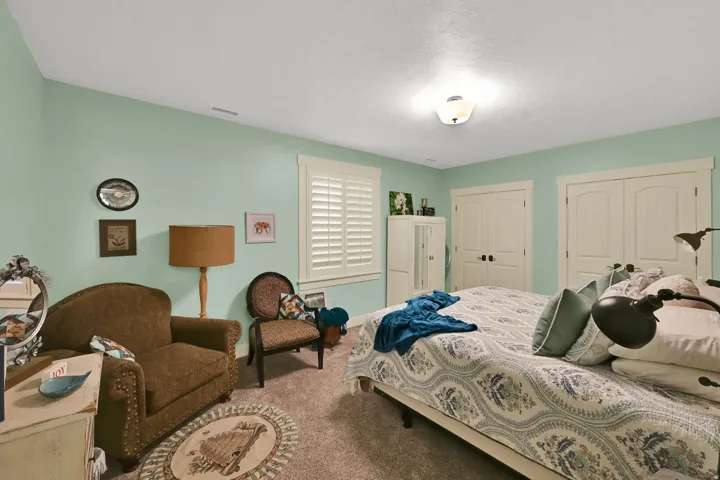 Spacious bedroom suite featuring soft sage-green walls, carpet flooring, recessed ceiling lighting, and multiple closet doors for storage