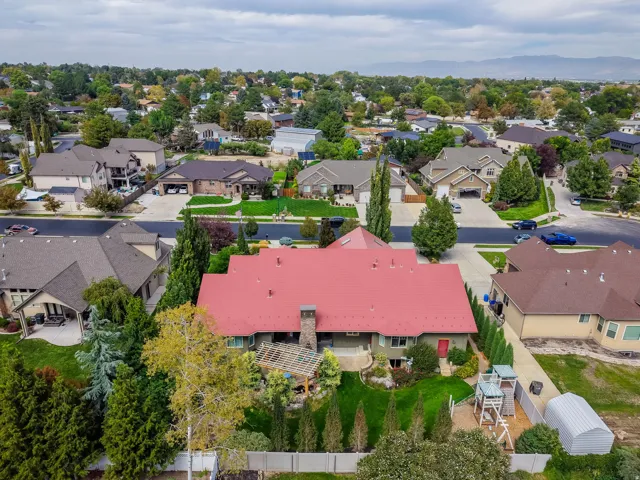 Red-toned roof and stone chimney with a lush green lawn and mature trees