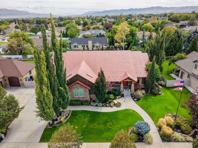 Expansive green lawn with mature landscaping, a curved concrete pathway, an ornate front entry, and a multi-gabled roofline