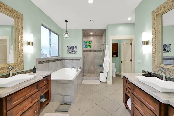 Dual wood-finish vanities with vessel sinks and light-toned countertops