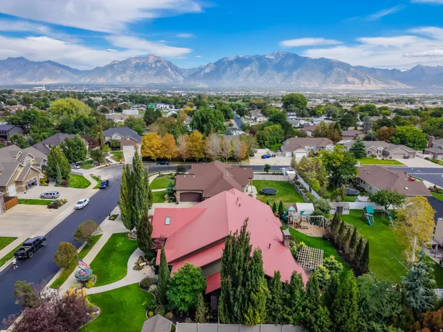 Aerial perspective showcasing a residential neighborhood with distant mountains, mature trees, and varying rooflines