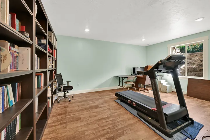 Integrated built-in shelving, wood-finish flooring, recessed lighting, and a bright window with a stone exterior detail