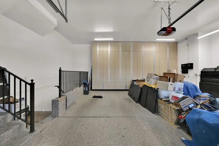 Attached garage with an epoxy-coated floor, extensive built-in cabinetry, and integrated overhead lighting