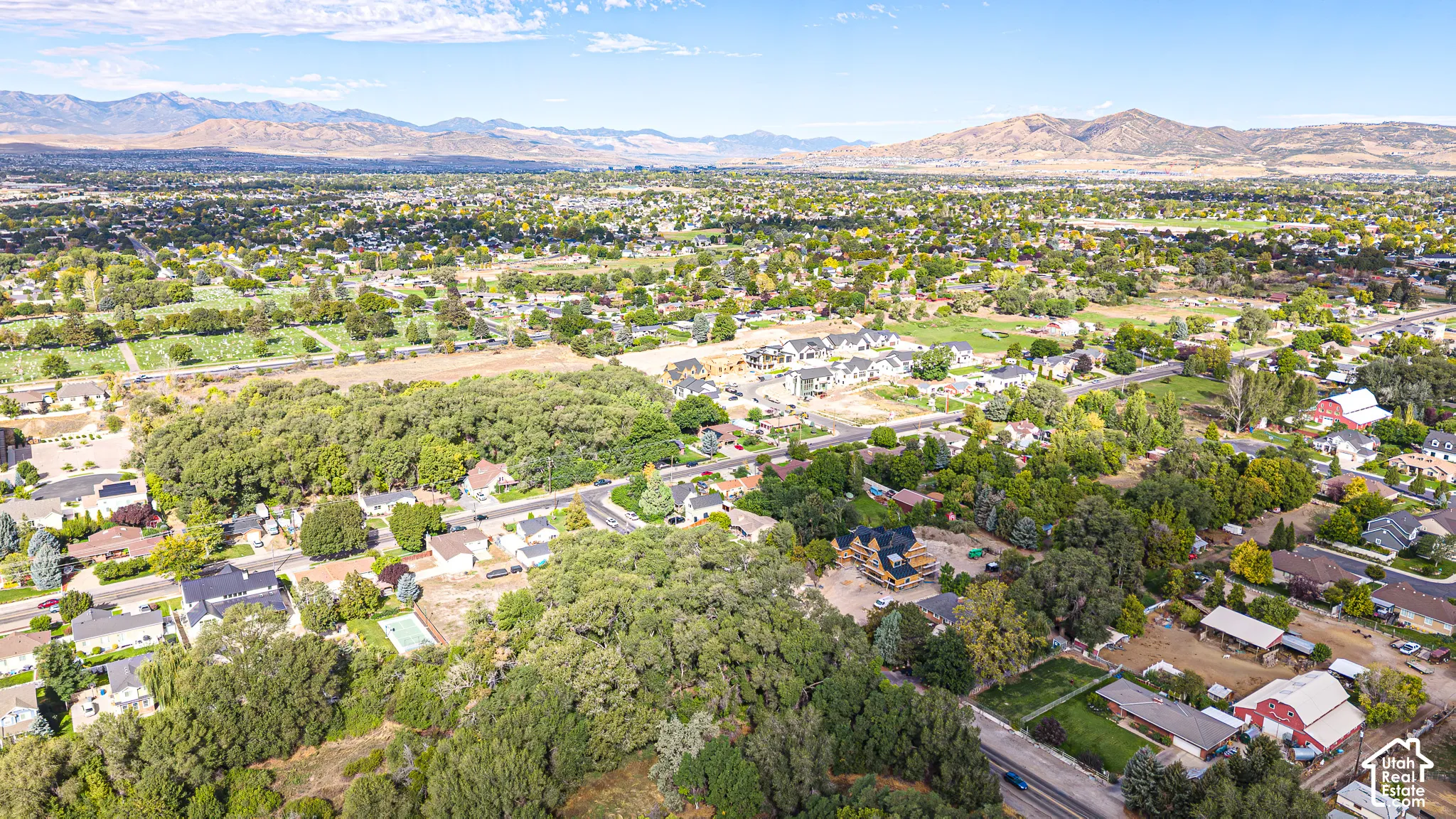 Expansive suburban landscape with varied housing styles, mature trees, and mountainous terrain in the distance