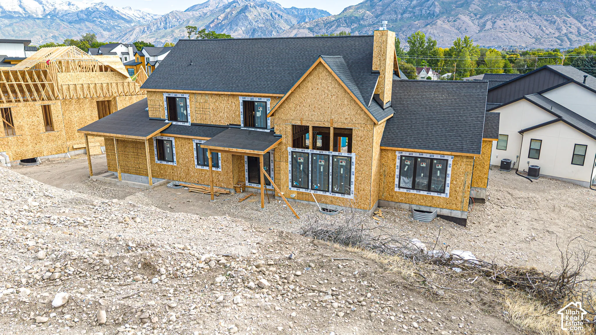 Newly constructed residence featuring a dark shingle roof, multiple gables, a covered porch, and black-framed windows
