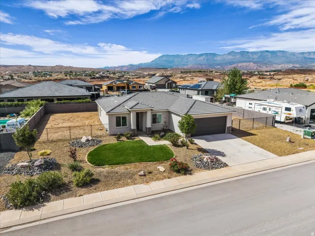 Contemporary single-story residence featuring a two-car garage, concrete driveway, and desert-adapted landscaping with a manicured lawn