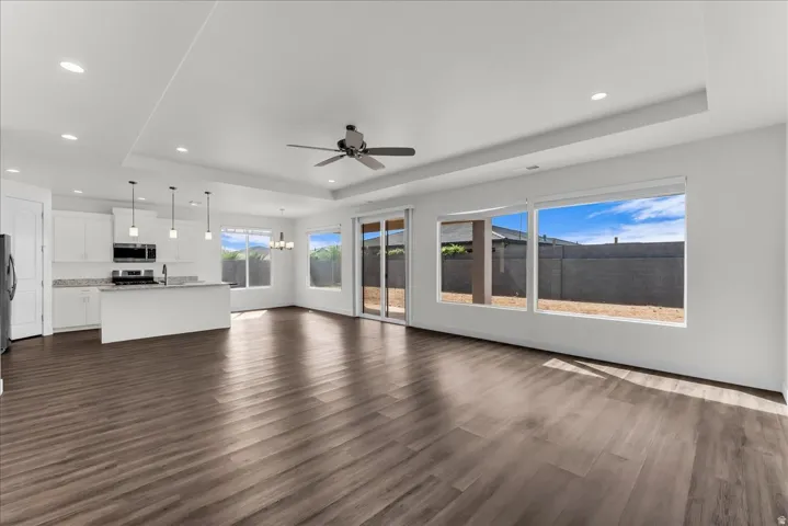 Open-concept living area featuring wood-finish flooring, recessed lighting, and a tray ceiling